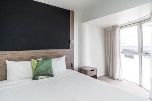 惠灵顿惠灵顿四中心美爵公寓式酒店的卧室设有一张大白色的床和大窗户