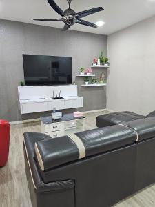 居銮TSK Homestay Taman Sri Kluang的客厅配有黑色真皮沙发和平面电视。