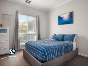 维克多港3BR Contemporary Home with Sea Views的一间卧室配有一张带蓝色棉被的床和窗户。