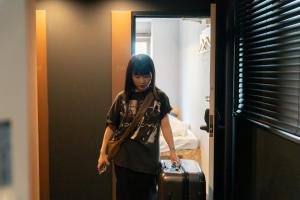 大阪3U NAMBA MINAMI by DOYANEN的带着手提箱走进房间的一个女人