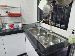 居銮TSK Homestay Taman Sri Kluang的厨房配有不锈钢水槽和锅