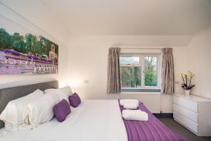 梅登黑德OYO Wilson Lodge的卧室配有一张带紫色枕头的大型白色床。