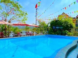 峰牙Phong Nha Escape Bungalow的度假村的游泳池配有桌子和遮阳伞