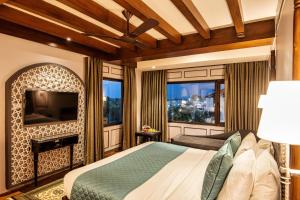 斯利那加The Vintage Srinagar at Dal Lake的一间卧室设有一张床、一台电视和窗户。