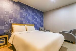济州市Aliba Hotel的一间卧室配有一张大床和两把椅子