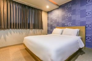 济州市Aliba Hotel的卧室配有一张白色大床和紫色墙壁
