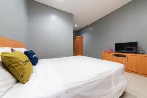 雅加达RedDoorz Plus near Kelapa Dua Kebon Jeruk的卧室配有白色床和黄色枕头