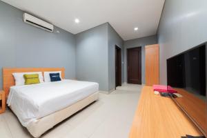 雅加达RedDoorz Plus near Kelapa Dua Kebon Jeruk的一间卧室配有一张床和一台平面电视