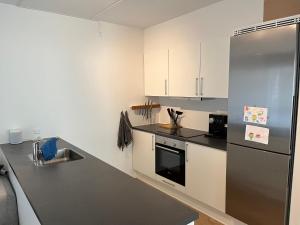 奥尔堡Charming Aalborg Apartment With parking的厨房配有白色橱柜和不锈钢冰箱