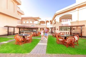 沙姆沙伊赫Pickalbatros Royal Moderna Sharm "Aqua Park"的两人在配有桌椅的大楼前行走