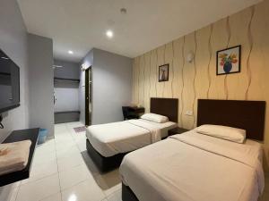Kampong Batu TigaM Three Hotel by SECOMS的酒店客房设有两张床和一台平面电视。