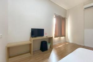 雅加达Urbanview Hotel Residence 446 Tanjung Duren的一间设有一张床和一张书桌上电视的房间