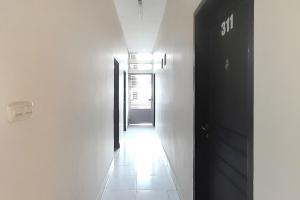 雅加达Urbanview Hotel Residence 446 Tanjung Duren的一条带白色墙壁和黑色门的走廊
