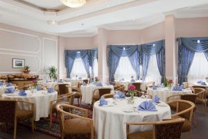 奈季兰Gloria Inn Najran的餐厅配有白色的桌椅和蓝色的窗帘