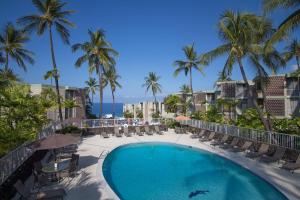 科纳Alii Villas Cozy 1BR Unit Near DT (5 Guests)的一个带椅子和棕榈树的游泳池以及大海