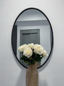 梅里达Apartamentos Lusitania Parking Gratis bajo disponibilidad的镜子前的白色玫瑰花瓶