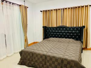 Ban Sam Bai Thao的一间卧室配有一张带黑色床头板和窗帘的床