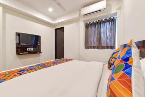 巴罗达FabHotel Shri Krishna的一间卧室配有一张床和一台平面电视
