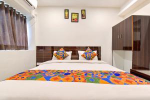 巴罗达FabHotel Shri Krishna的一间卧室配有一张特大号床和五颜六色的被子