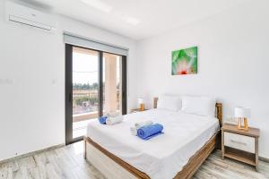 KtimaVilla Elpida TWO by Ezoria Villas in Timi, Paphos的白色的卧室设有一张大床和一个窗户