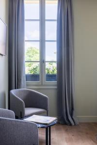 圣艾米隆Hotel Porte Brunet的客厅配有椅子和窗户