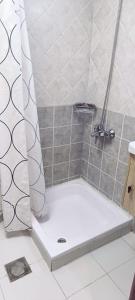 富查伊拉Clifton International Hotel的设有带白色浴缸的淋浴的浴室