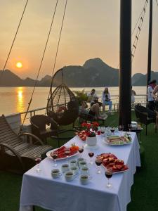 河内Bông Hà Nội hostel的船上的餐桌,上面摆放着食物和酒杯