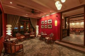 会安Cozy Savvy Boutique Hotel Hoi An的餐厅拥有红色的墙壁和桌椅
