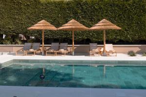 福斯Malates Slow Boutique Hotel的一个带遮阳伞和躺椅的游泳池以及一个游泳池