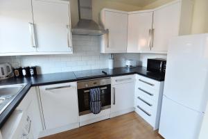 克劳利Luxury 2 BR Fully Furnished Flat in Crawley - 2 FREE Parking Spaces的厨房配有白色橱柜和炉灶烤箱。