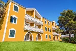 萨卡莱塔Vibra Blanc Palace Aparthotel的一座大型橙色建筑,前面有一个绿色草坪