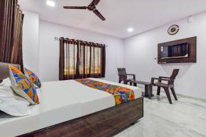 艾哈迈达巴德FabHotel Vishwa Palace的卧室配有一张床和一张桌子及椅子