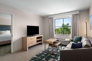 西棕榈滩西棕榈滩希尔顿惠庭套房酒店的酒店客房设有沙发、电视和床。