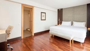 巴塞罗那NH巴塞罗那体育场酒店的一间卧室配有一张床、一张桌子和一把椅子