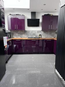 埃布韦尔Modern Newly Renovated 3 Story House in Ebbw Vale的厨房配有紫色橱柜和瓷砖地板。