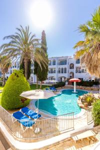 萨卡莱塔Vibra Caleta Playa Apartmentos-3SUP的一座带椅子和遮阳伞的游泳池以及一座建筑