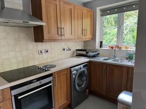 邓斯特布尔Grove flat - two bedroom flat in central Dunstable的厨房配有木制橱柜、洗衣机和烘干机