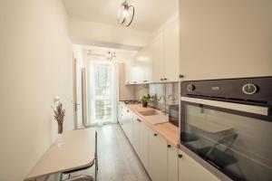 雅西COZY APARTHOTEL - Ultracentral Luxury Apartments Iasi的厨房配有白色橱柜和黑炉灶烤箱。