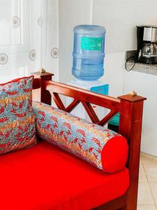马林迪Mawingu Loft的一张红色沙发,在柜台上装有一瓶水