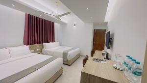 达卡Priyo Nibash Stylish Residential Hotel的酒店客房设有两张床和电视。