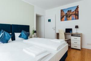 汉堡Hanseat Apartments的一间卧室配有一张带蓝色枕头的大床和一张书桌