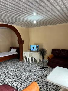 弗里敦Yogi Home Stay Near Freetown Airport的一间配备有沙发及一张桌子及电视的客房
