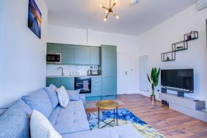 滨海绍森德132 Qweens Stay的一间带蓝色沙发的客厅和一间厨房