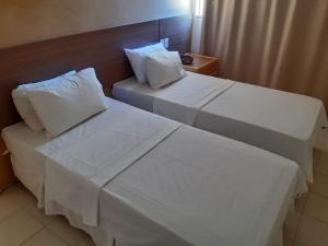 萨尔瓦多Samba Villa da Praia的配有2张床铺的酒店客房,提供白色床单和枕头
