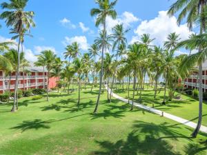 蓬塔卡纳全包巴塞罗巴瓦罗海滩客房 - 仅限成人入住的一座棕榈树公园,位于一座建筑前