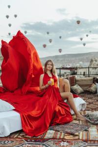 格雷梅Angel View Suites的穿着红色衣服的女人坐在一张带红伞的床上