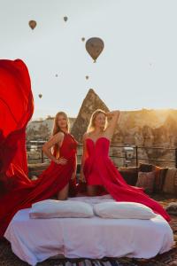 格雷梅Angel View Suites的两个穿着红色衣服的女人坐在金字塔的床上