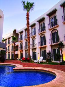 卡波圣卢卡斯Seven Crown Express & Suites by Kavia的一座带游泳池的建筑前的棕榈树