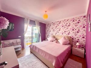奥良Belle suite / belles vacances的一间卧室设有紫色的墙壁和一张粉红色床单。