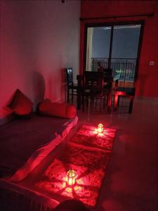 BāruipurTani s Homestay的红色的房间,地板上设有一张带两个蜡烛的床